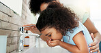 Girl, mom and child cleaning mouth for hygiene, morning routine or teaching healthy oral habits in home. Parent, washing or kid learning dental care in bathroom with basin water, mother and support 