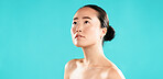 Thinking, woman and natural beauty in studio with skincare treatment results, healthy glow and skin hydration. Mockup space, asian girl and confidence with dermatology or self care on blue background