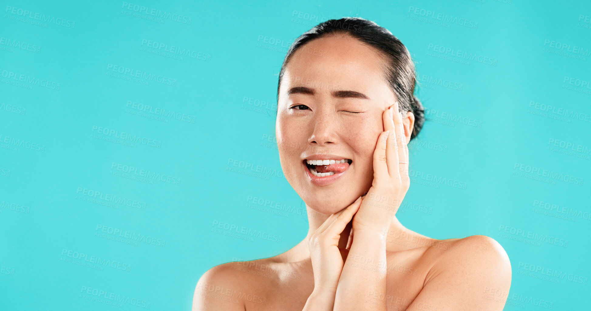 Buy stock photo Wink, skincare and portrait of Asian woman in studio for wellness, cosmetics and facial treatment. Dermatology, mockup space and person with emoji for health, salon and beauty on blue background