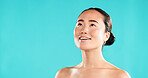 Beauty, skincare and Asian woman in studio thinking for choice for cosmetics, wellness and facial treatment. Dermatology, mockup space and person for health, grooming or decision on blue background
