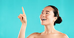 Beauty, skincare and Asian woman in studio pointing for choice for cosmetics, wellness and facial treatment. Dermatology, spa and girl with gesture for health, grooming or decision on blue background