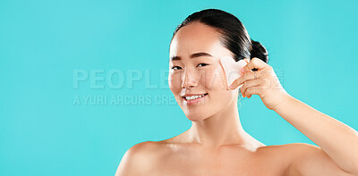 Buy stock photo Beauty, portrait and woman with gua sha in studio for lymphatic drainage, wrinkle reduction or self care routine. Mockup space, Asian girl or smile with cosmetics tool for skincare on blue background