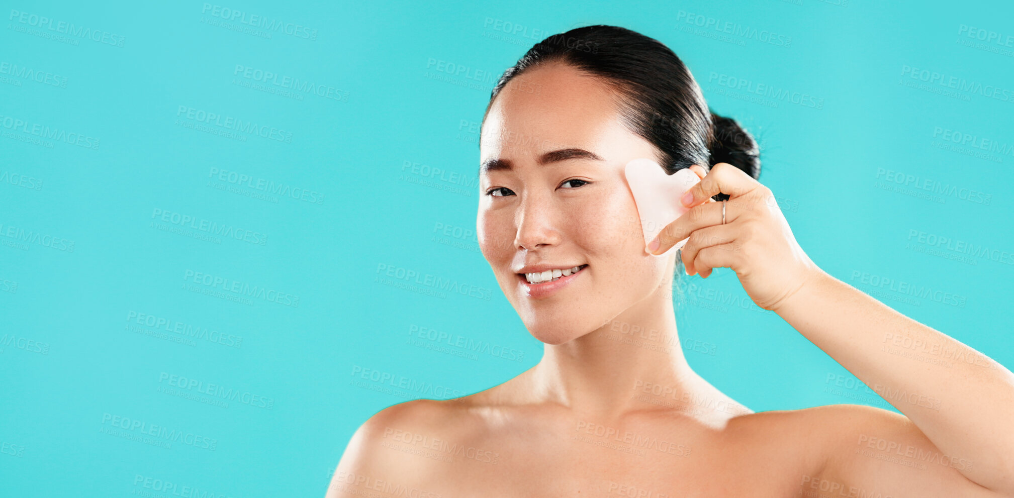 Buy stock photo Beauty, portrait and woman with gua sha in studio for lymphatic drainage, wrinkle reduction or self care routine. Mockup space, Asian girl or smile with cosmetics tool for skincare on blue background