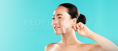 Buy stock photo Beauty, woman or rose quartz roller in studio for lymphatic drainage, puffiness reduction or self care routine. Mockup space, Asian person or happy with cosmetics tool for skincare on blue background