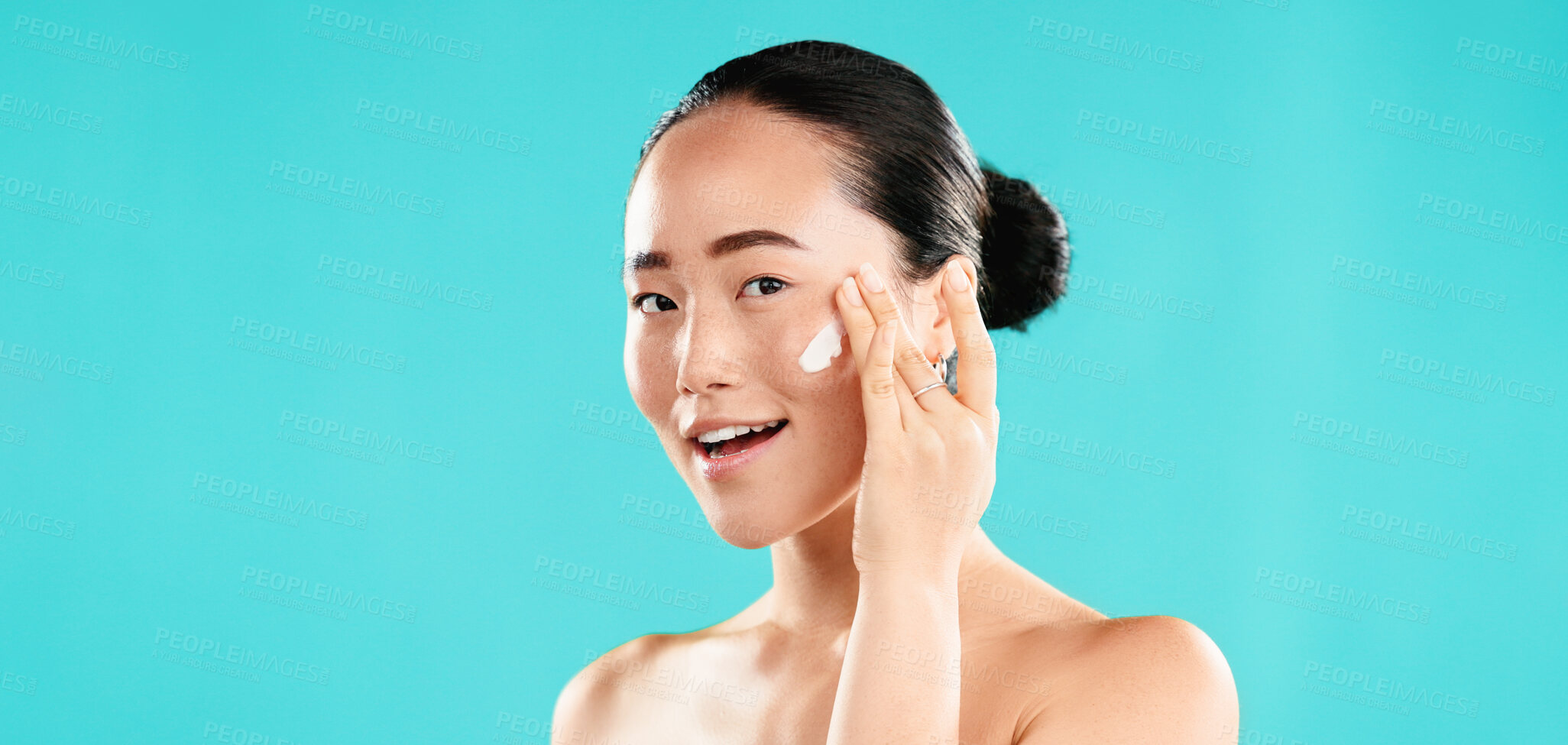 Buy stock photo Studio, portrait and Asian woman with cream for skincare, wellness and anti aging benefits with smile. Mockup, female person and apply with cosmetics for beauty, face moisturizer and blue background