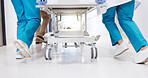 Running, hospital and doctors with gurney for emergency, surgery and help for medical service. Healthcare, er and feet of people rush with bed for accident, operation or surgical treatment in hallway