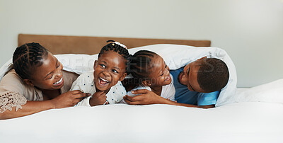Buy stock photo Tickle, laughing and love with black family in bedroom for support, bonding and funny. Happiness, relax and trust with parents and children at home for playful, comedy and affection together