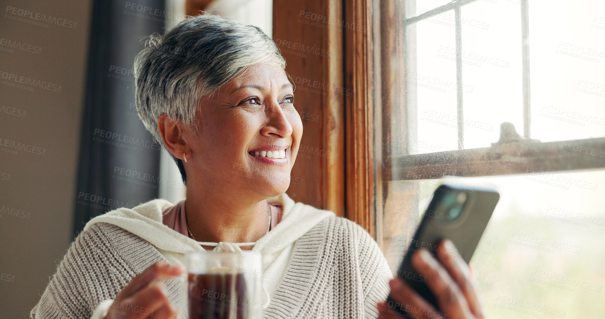 Buy stock photo Mature woman, thinking and phone by window, reflection and inspiration with self help quote on social media. Person, happy and smartphone with perspective, memory and mobile app with coffee in home