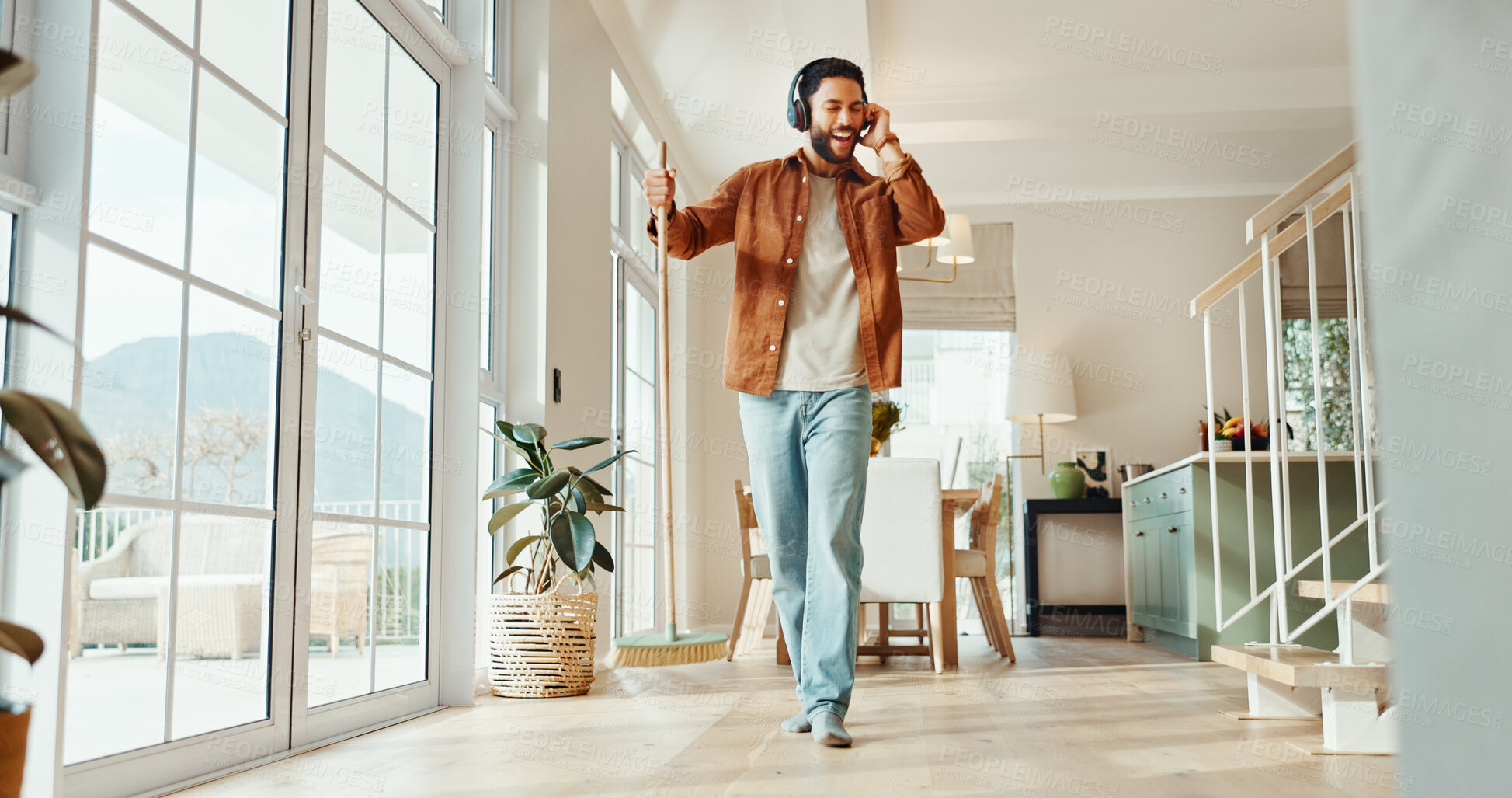Buy stock photo Man, singing and headphones with cleaning in home for sweeping music, housekeeping playlist and energy. Dancing, person and broom with audio track for housework, domestic chores and streaming sound