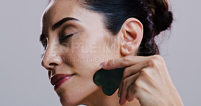 Buy stock photo Beauty, facial massage and stone of woman in studio for antiaging cosmetics or dermatology. Gua sha, natural product and skincare with person isolated on gray background for crystal face treatment