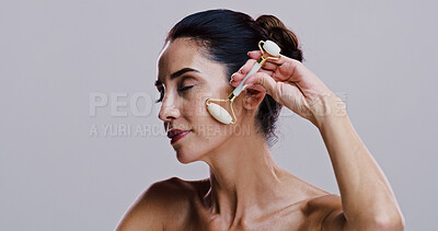 Buy stock photo Beauty, facial roller and portrait of woman in studio for antiaging cosmetics or dermatology. Crystal, gua sha and skincare with person isolated on gray background for face massage treatment