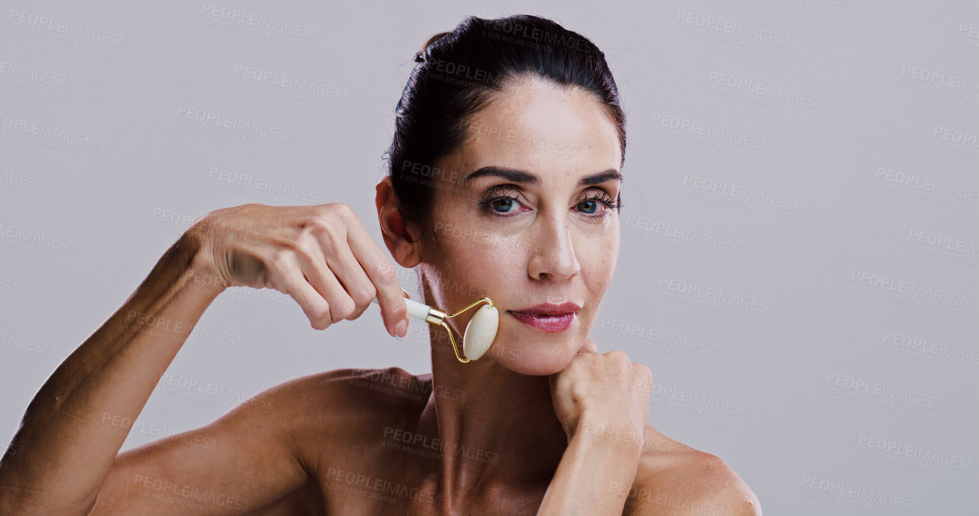 Buy stock photo Beauty, roller and portrait of woman in studio for antiaging cosmetics or dermatology. Gua sha, massage and skincare with person isolated on gray background for crystal stone facial treatment