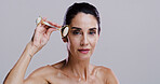 Derma roller, portrait and skincare with woman in studio for antiaging cosmetics or dermatology. Beauty, gua sha and massage with person isolated on gray background for crystal stone face treatment