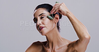Buy stock photo Beauty, facial and jade roller with woman in studio for antiaging cosmetics or dermatology. Gua sha, massage tool and skincare with person isolated on gray background for crystal stone face treatment