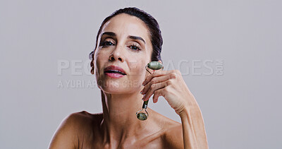 Buy stock photo Beauty, jade roller and portrait of woman in studio for antiaging cosmetics or dermatology. Gua sha, facial massage and skincare with person on gray background space for crystal stone face treatment