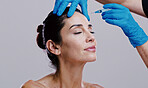 Woman, skincare and needle in studio for dermal filler, relax and antiaging treatment. Mature model, surgeon hands or injection on white background for cosmetology, transformation or plastic surgery