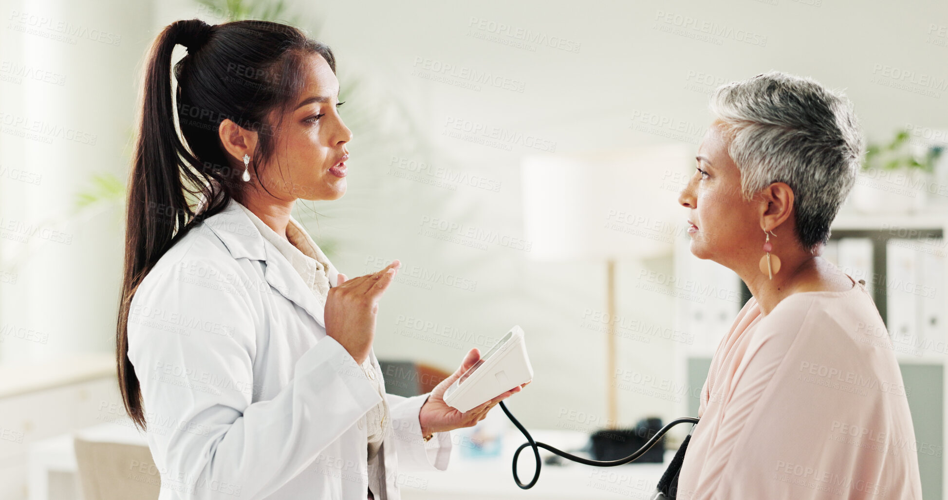 Buy stock photo Consultation, blood pressure and doctor with mature woman at hospital or clinic for healthcare. Discussion, exam and patient with medical professional for check up for heart health, advice and care