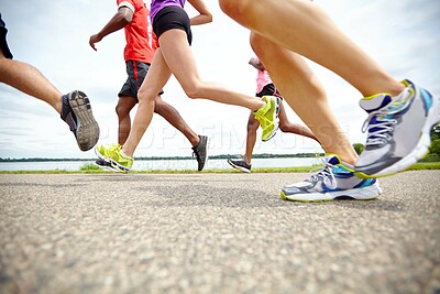 Fitness, legs and group of people running on track for race, challenge or marathon with speed. Sports, energy and body of athletes with energy for cardio workout, exercise or training at stadium.