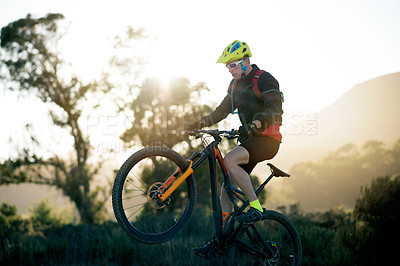Buy stock photo Balance, bike and off road with man in mountains for outdoor adrenaline, adventure or training. Exercise, fitness and wheelie with person cycling in nature for challenge, competition or performance