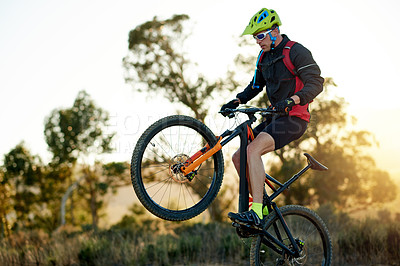 Buy stock photo Balance, bike and jump with man in mountains for adrenaline, adventure or training off road. Exercise, fitness and wheelie trick with sports person cycling in nature for challenge or performance
