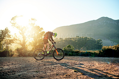 Buy stock photo Bike, sport and sunset with man in mountains for outdoor adrenaline, adventure or training. Exercise, fitness or sports and person cycling off road in nature for challenge, competition or performance
