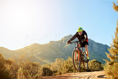 Buy stock photo Man, mountain bike and jump with sunshine on dirt road for adrenaline rush, fitness or extreme sport in nature. Male person, cyclist or riding with bicycle for stunt or cardio on path, trail or space