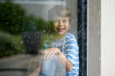 Buy stock photo Happy, child and watching rain by window for sensory experience, imagination and winter weather view. Boy kid, smile and thinking in home with daydreaming, memory and checking scenery with reflection