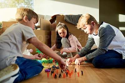 Buy stock photo Boxes, moving and kids with toys in new home for fun, bonding and sibling time for development. Growth, cardboard and girl kid teaching brothers to play with trinkets for game in family house.