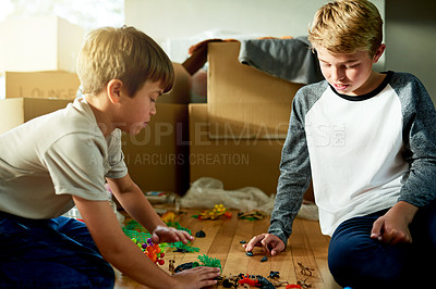 Buy stock photo Boxes, moving and children with toys in new home for fun, bonding and sibling time for development. Growth, cardboard and boy kid teaching brother to play with trinkets for game in family house.