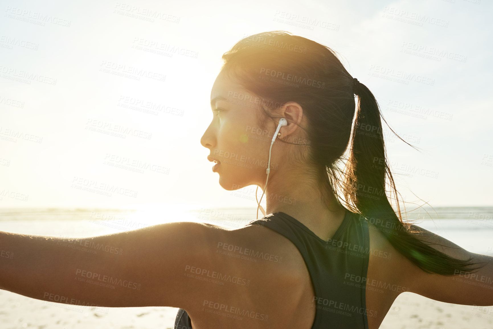 Buy stock photo Yoga, back or woman at sea in warrior pose for posture and fitness health for wellness. Music earphones, pilates or female person stretching arms at beach for mindfulness, balance or outdoor workout