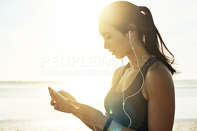 Buy stock photo Woman, phone and music on beach for fitness, streaming service and online exercise tutorial. Athlete, mobile and earphones at ocean for motivational podcast, workout playlist or wellness tracking app