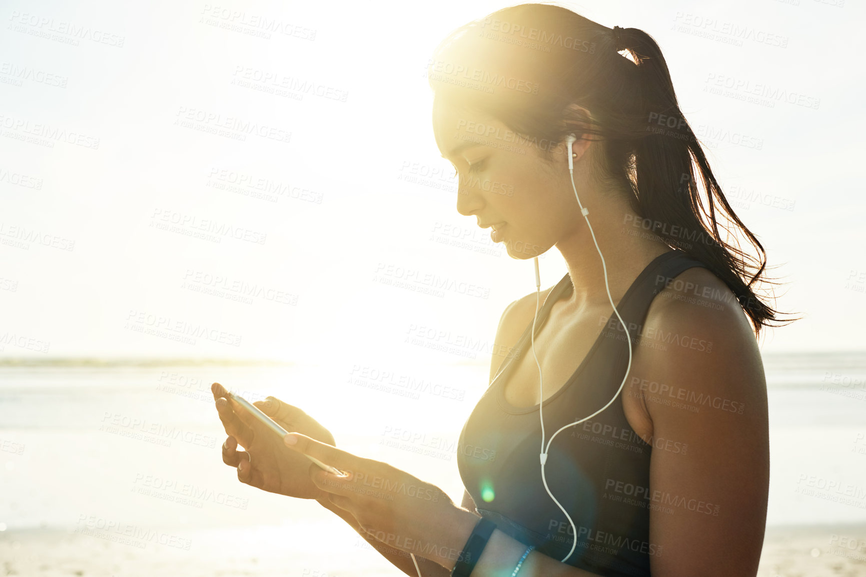 Buy stock photo Woman, phone and music on beach for fitness, streaming service and online exercise tutorial. Athlete, mobile and earphones at ocean for motivational podcast, workout playlist or wellness tracking app