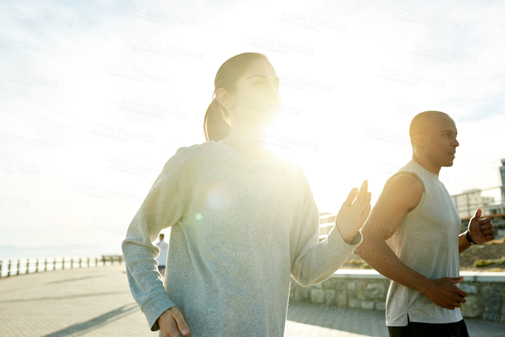Buy stock photo Couple, team and running fitness by sea, workout collaboration and sports support by ocean. People, sun flare and training for marathon together on promenade, cardio challenge and athletes exercise