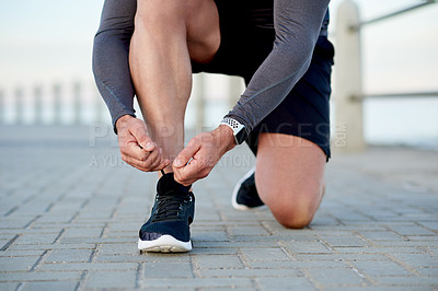 Buy stock photo Man, athlete and tie shoelace by beach, sports preparation and outdoor for marathon training. Male person, sneakers and getting ready for cardio challenge on sea promenade, runner and start workout