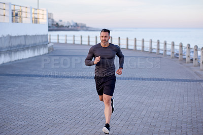 Buy stock photo Mature man, running and action on beach promenade, sports workout and activity for mobility health. Male person, physical challenge and training for marathon, outdoor and cardiovascular exercise