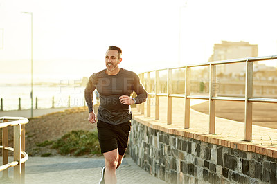 Buy stock photo Mature man, running and athlete on beach promenade, sports workout and activity for mobility health. Male person, physical challenge and training for marathon, outdoor and cardiovascular exercise