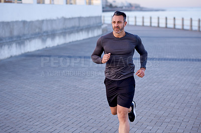 Buy stock photo Mature man, running and fitness on beach promenade, sports workout and activity for mobility health. Male person, physical challenge and training for marathon, outdoor and cardiovascular exercise