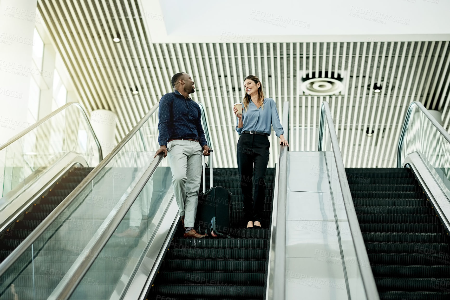 Buy stock photo Business man, woman and conversation on escalator at airport for travel with luggage, coffee and smile. People, assistant or partner for talk on auto stairs for trip, schedule and booking at terminal