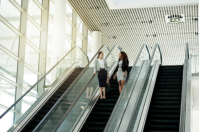 Buy stock photo Office, escalator and business women in conversation in lobby for meeting, discussion and networking. Professional, corporate and people on stairs at conference, convention and seminar in building