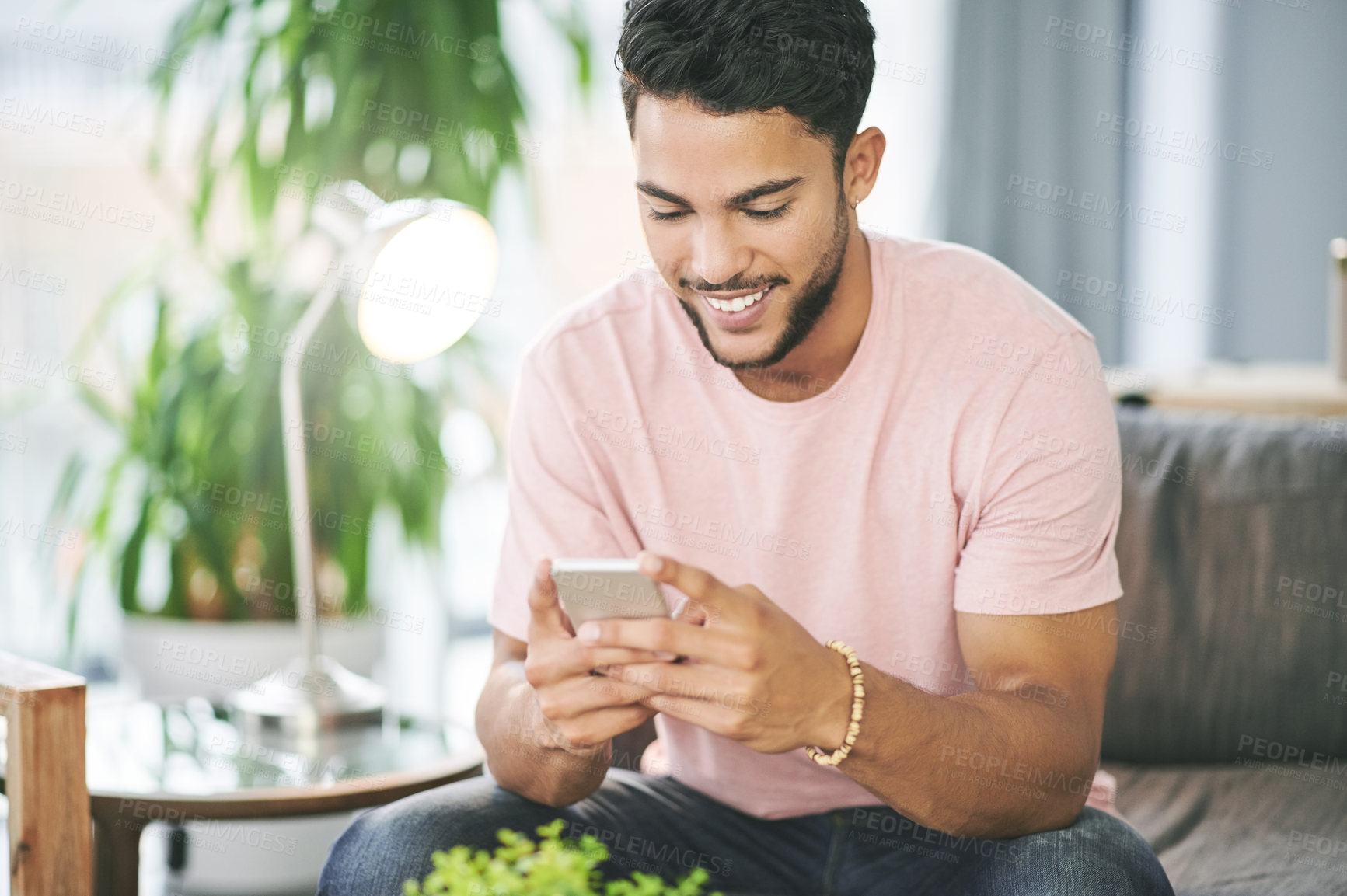 Buy stock photo Home, typing and man on couch, cellphone and smile with social media, text and message to contact. Person, connection and email notification with smartphone, online reading and funny meme in lounge