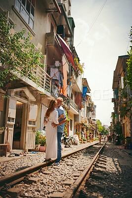 Buy stock photo Happy couple, kiss and railway in city for holiday, bonding together and honeymoon as travel. Woman, man and train track in town for vacation destination, sightseeing or outdoor as romance in Vietnam