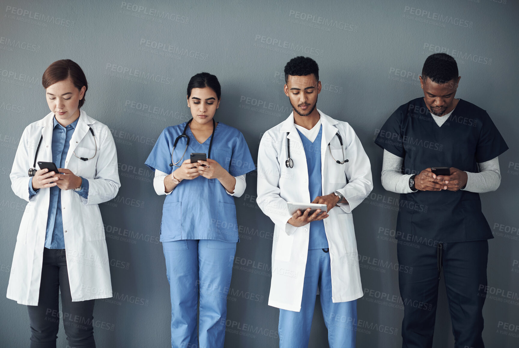 Buy stock photo Doctor, teamwork and technology for medical research, planning and telehealth services on wall background. Healthcare worker, group and nurse typing, reading and scroll on mobile or tablet for clinic