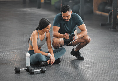 Buy stock photo Personal trainer, coach or fitness instructor helping an active and fit woman in the gym. Young female athlete sitting down and managing her workout routine or schedule with her exercising partner