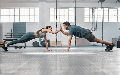 Buy stock photo Fitness partners exercising together and doing pushups high five at the gym. Fit and active man and woman training in a health facility as part of their workout routine. A couple doing an exercise