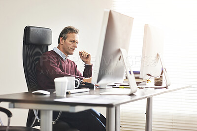 Buy stock photo A businessman using a computer in a modern office. A mature male executive working online for business at his desk