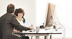 Two colleagues talking finance in a modern office. A mature businessman and businesswoman working with paperwork, discussing business matters