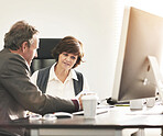 Two colleagues talking finance in a modern office. A mature businessman and businesswoman working with paperwork, discussing business matters