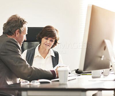 Buy stock photo Two colleagues talking finance in a modern office. A mature businessman and businesswoman working with paperwork, discussing business matters