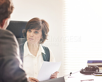 Buy stock photo Two colleagues talking finance in a modern office. A mature businessman and businesswoman working with paperwork, discussing business matters