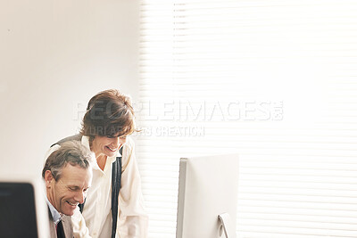 Buy stock photo Two colleagues using a computer in a modern office. A mature businessman and businesswoman working online, talking about business matters